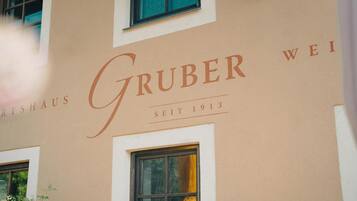 A building facade with the name 'Gruber Wei' and the year '1913' indicating the establishment year.