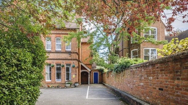 A brick building with a central courtyard, a blue door, and a brick wall with climbing plants. - St. Margaret's Hotel (Oxford)
