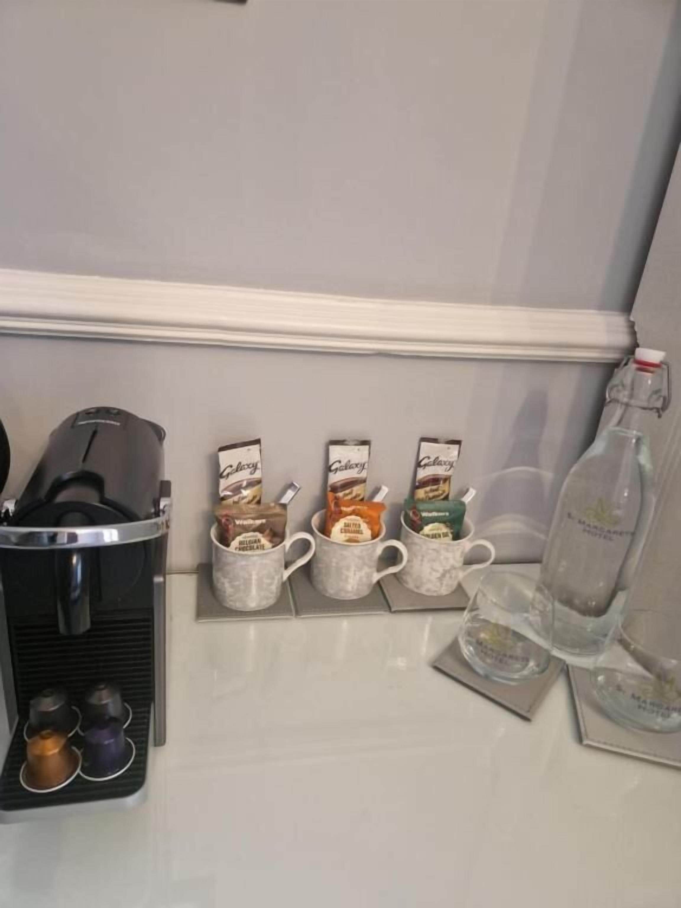 A coffee station with a coffee machine, a tray of coffee cups, and a bottle of water.