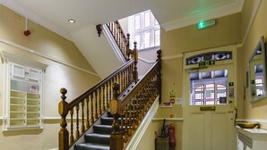 A staircase with wooden balusters, carpeted steps, and a fire exit sign. - St. Margaret's Hotel (Oxford)