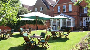 A patio with outdoor seating, a conservatory, and a brick house in the background. - St. Margaret's Hotel (Oxford)