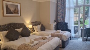 A hotel room with two beds, a chandelier, a window with curtains, and a framed picture on the wall. - St. Margaret's Hotel (Oxford)