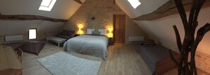 Un dormitorio acogedor en el ático con techo inclinado, una cama, una mesita pequeña y dos sillas.
