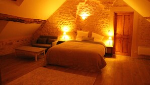 Un dormitori d'àtic acollidor amb sostre inclinat, un llit, una tauleta de nit, una làmpada i una porta de fusta.