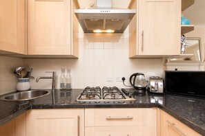 A kitchen with a gas stove, a toaster, and a sink.