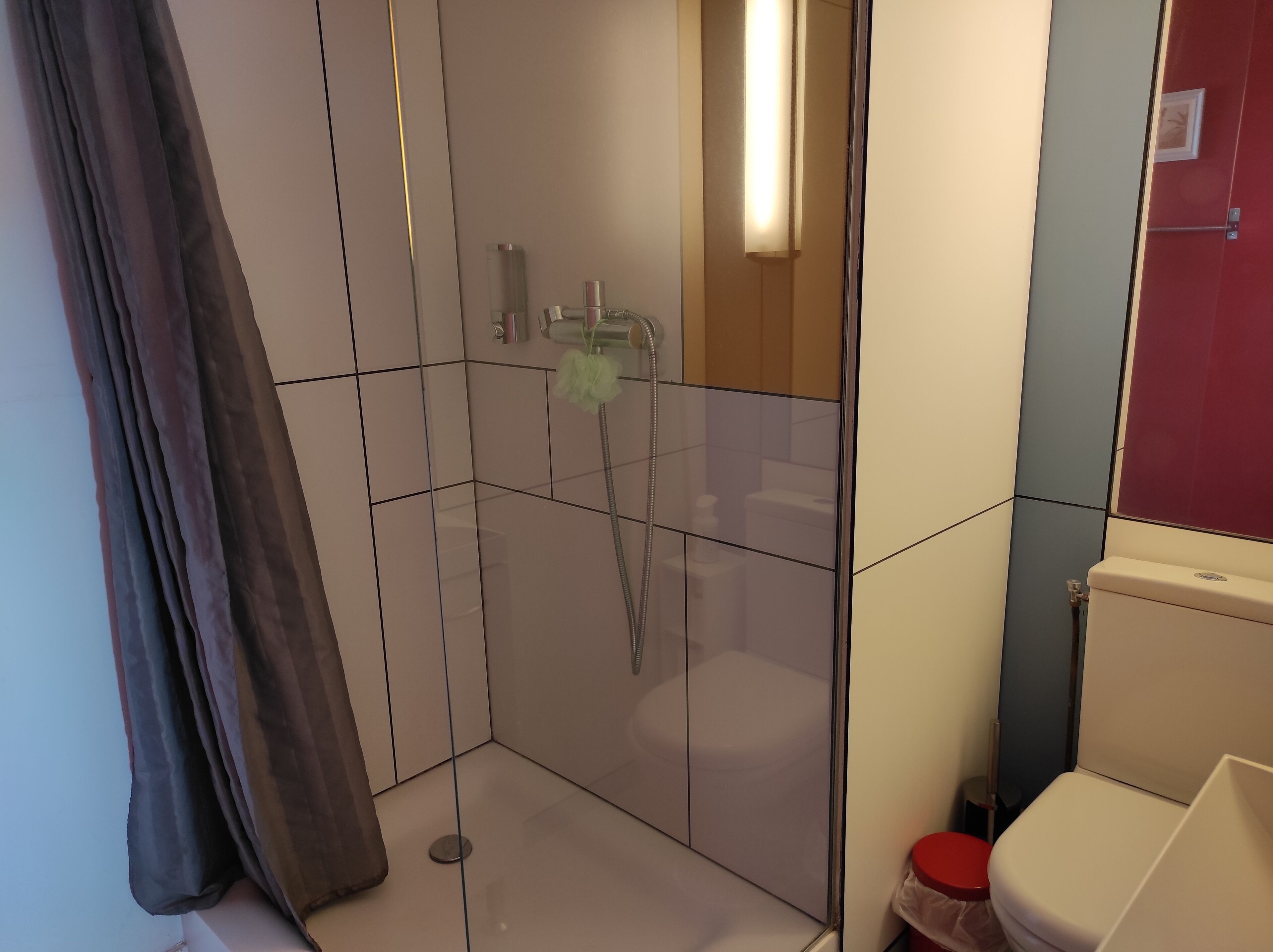 Et moderne badeværelse med et glasafskærmet brusebad, et toilet og en vask.