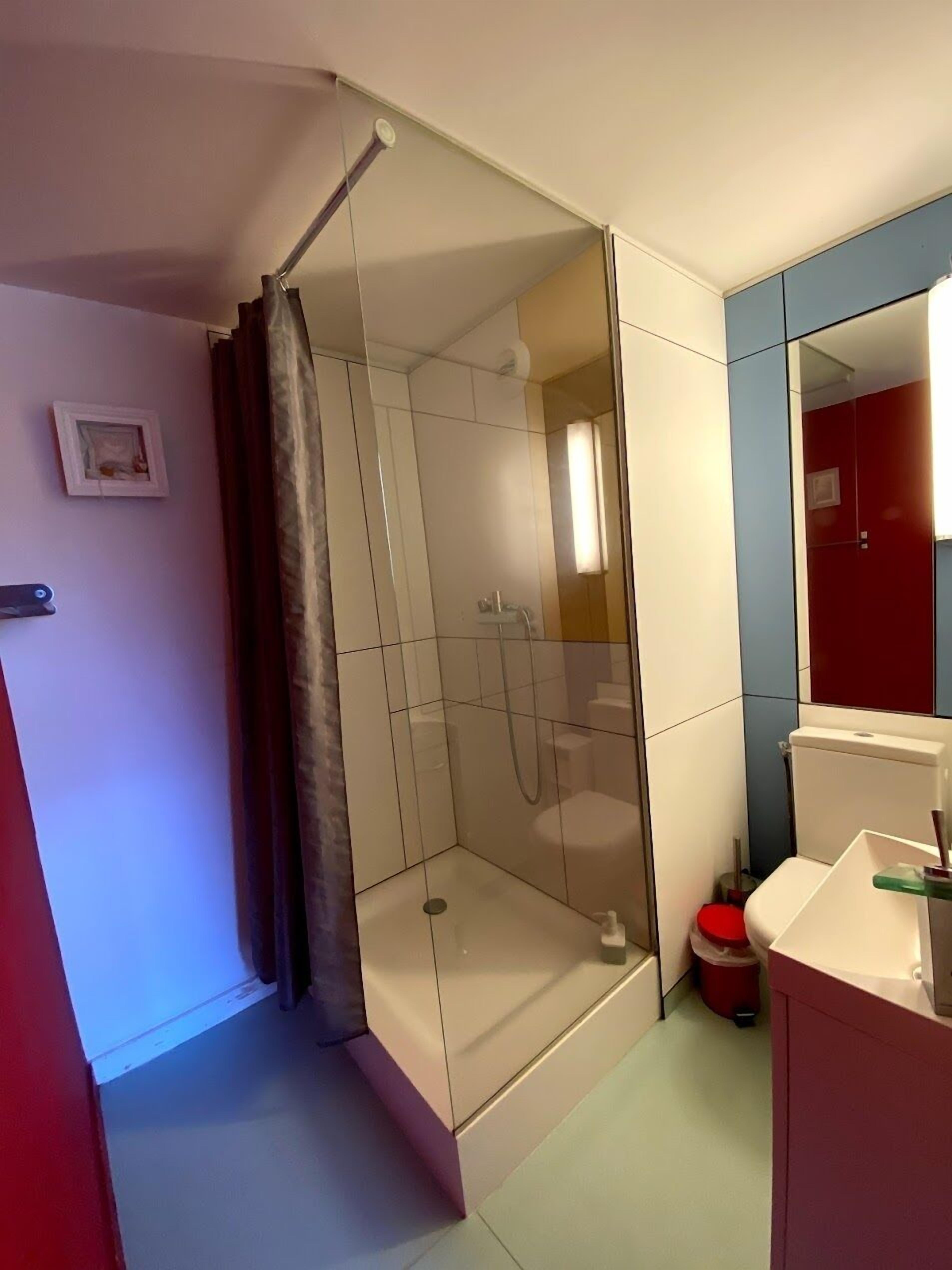 A modern bathroom with a glass-enclosed shower, a toilet, and a sink.