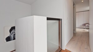 A modern interior with a minimalist design, featuring a glass partition, a wooden floor, and a small seating area with a chair. - Double Penthouse en suite - hiphipstay (Dublin)