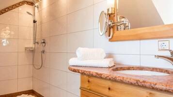 A bathroom with a shower, a sink with a wooden vanity, and a large mirror.