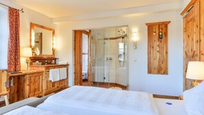 A hotel room with a wooden dresser, a mirror, a shower, and a bed with white linens. - Landgasthof zum Erdinger Weissbrau (Rosenheim)