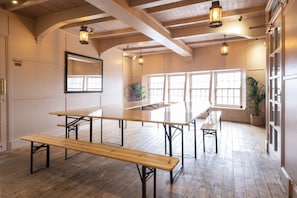 A spacious room with wooden floors, large windows, and multiple tables and benches. - The Wheelhouse (St Austell)