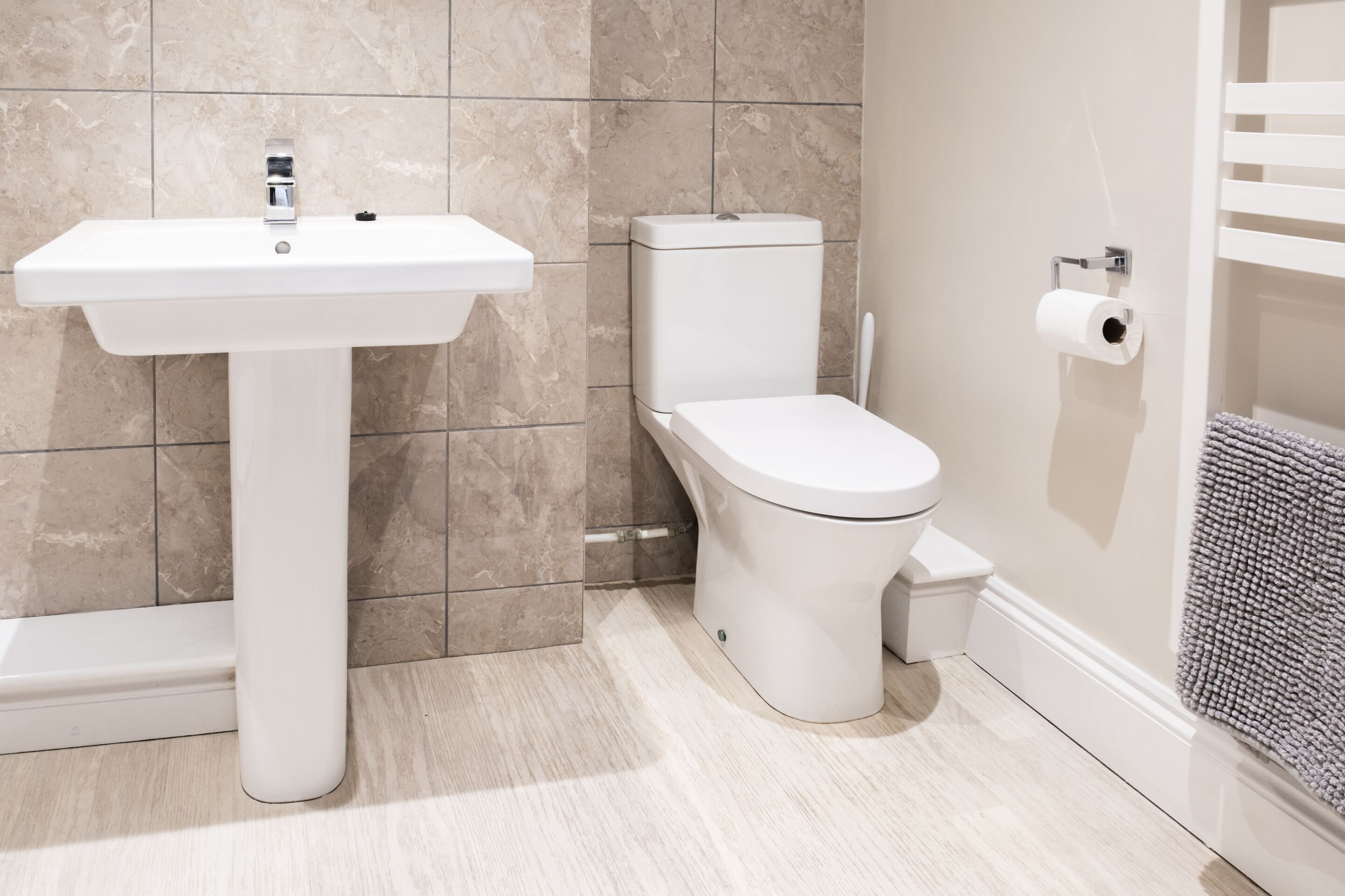 Un bany amb un lavabo blanc, un vàter i un penjador de tovalloles.