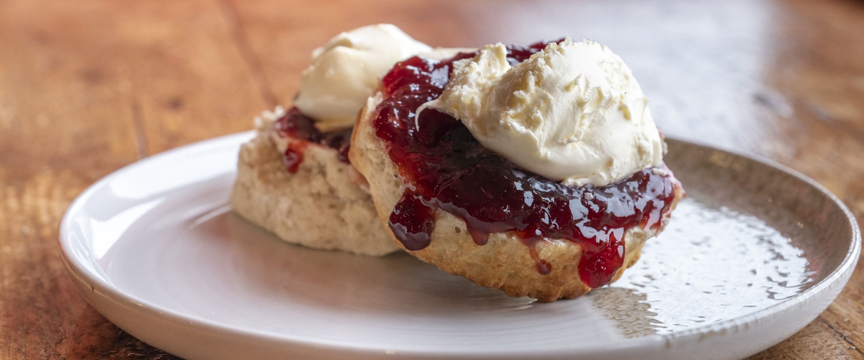 Ein Teller mit zwei Scones, belegt mit Marmelade und einer Kugel Eis.
