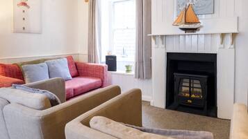 A living room with a sofa, armchairs, a fireplace, and a window with curtains.
