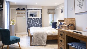 A bedroom with a bed, a desk, a chair, a dresser, a mirror, and a window with blinds.