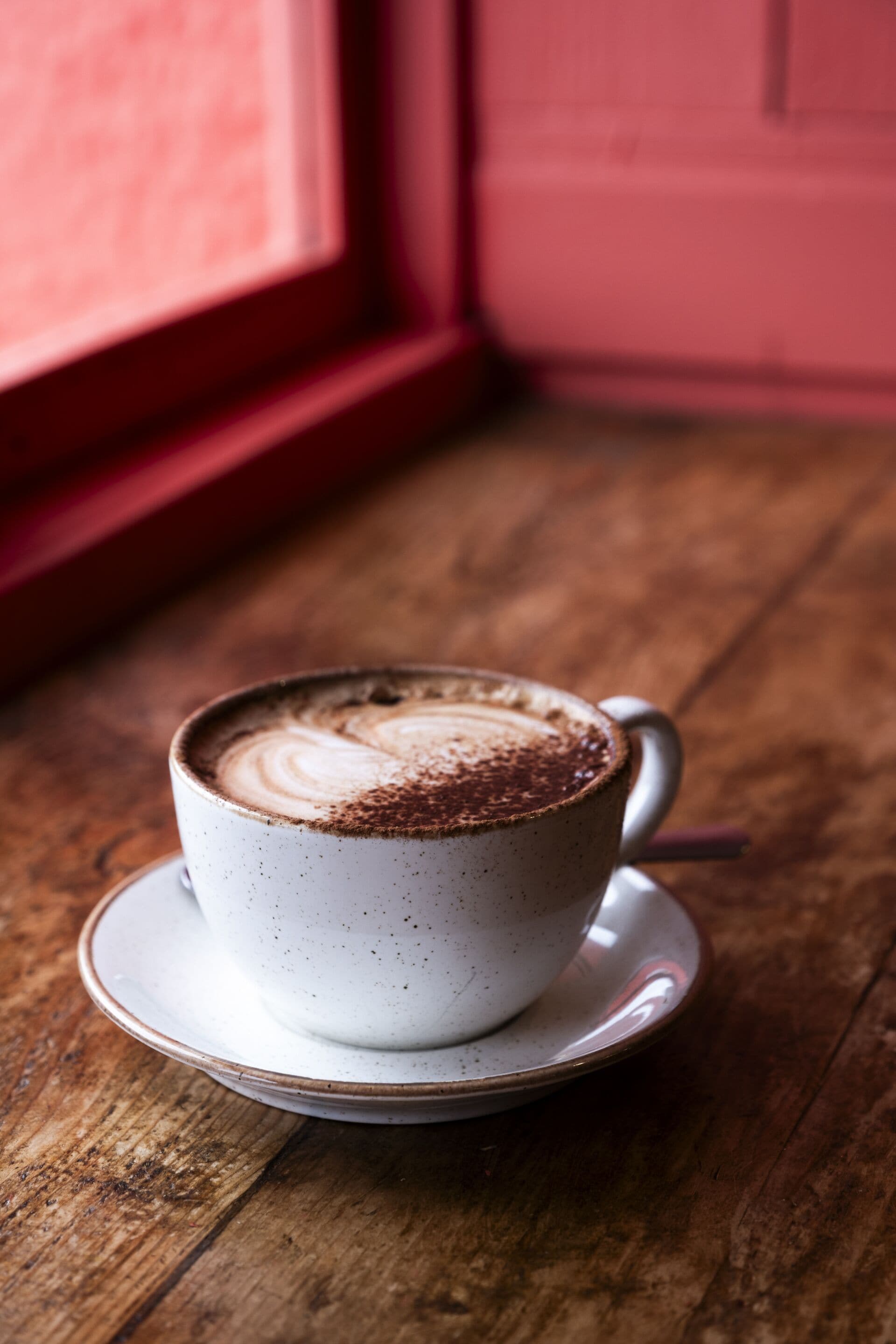 Una taza de café sobre un platito en una mesa de madera.