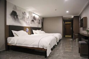 Habitación de hotel con una cama grande, un escritorio y un televisor montado en la pared.