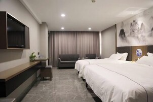 Una habitación de hotel con cama, escritorio, silla, televisor y un cuadro en la pared.