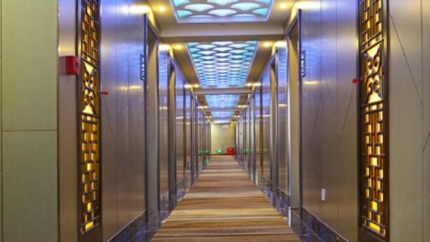 A long, narrow hallway with a patterned ceiling and glass doors on both sides.