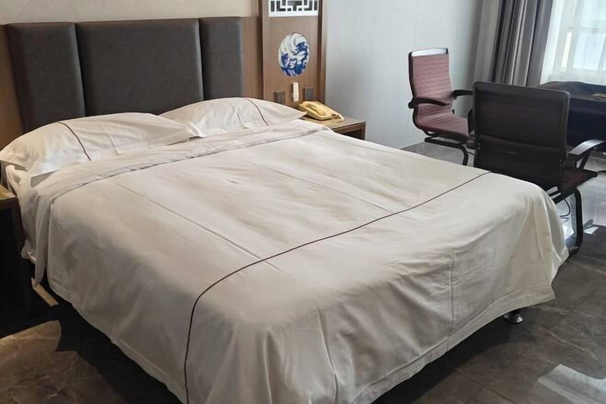 Ein Hotelzimmer mit einem großen Bett, einem Schreibtisch, einem Sessel und einem Telefon.