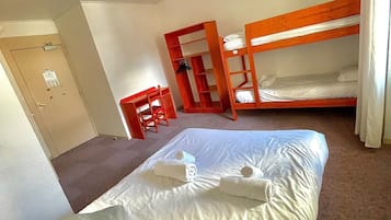 A room with a bunk bed, a single bed, and a chair.