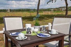 Une table en bois installée à l’extérieur, avec des chaises, une plante et un service à thé.