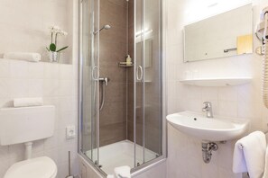 A modern bathroom with a glass-enclosed shower, a white sink, and a toilet.