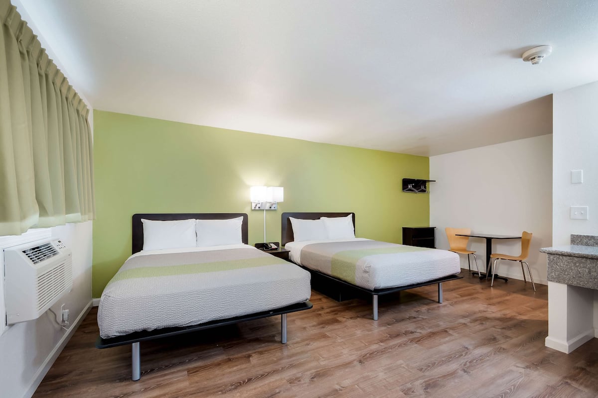 A hotel room with two beds, a desk, and a chair.