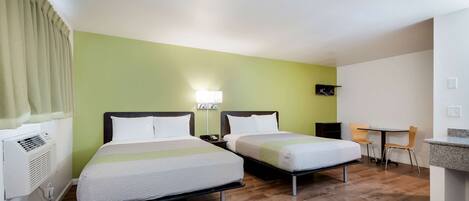 A hotel room with two beds, a desk, and a chair.