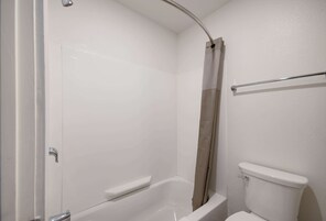 Un baño con una bañera blanca, un inodoro y una cortina de ducha.