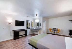 A hotel room with a bed, a desk, a chair, a TV, a mirror, and a bathroom. - Motel 6 Burlington, WA (Burlington)