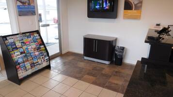 A reception area with a digital screen, a map display, a trash bin, and a small cabinet.