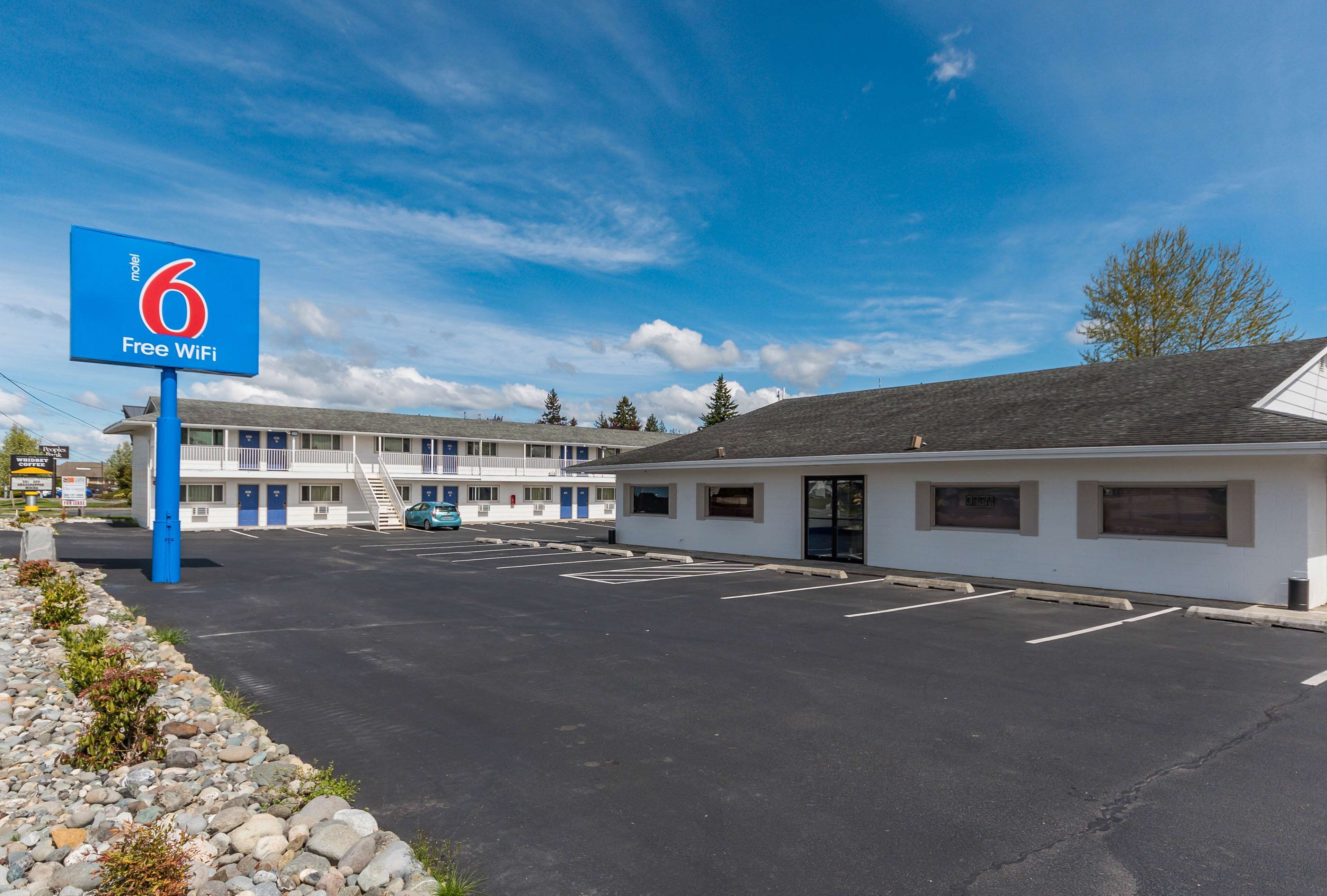 Un motel avec une enseigne indiquant que le Wi-Fi est gratuit, un parking et un bâtiment comprenant plusieurs chambres.