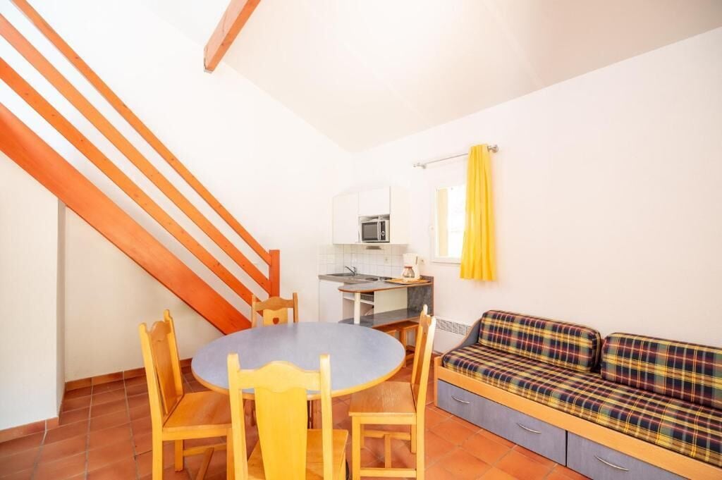 Un espace de vie compact comprenant un coin repas, une kitchenette et un canapé.
