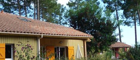 A yellow building with a tiled roof, a porch, and a bicycle parked outside.