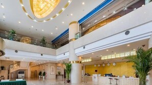 A multi-level hotel lobby with a reception desk, seating area, and decorative lighting.