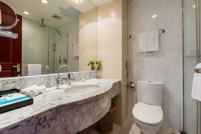 Un baño moderno con lavamanos de mármol, cabina de ducha con vidrio y inodoro blanco.