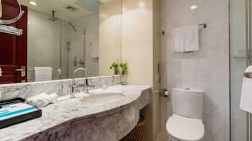 Un baño moderno con lavamanos de mármol, cabina de ducha con vidrio y inodoro blanco.