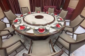 A round dining table with chairs, set for a meal.