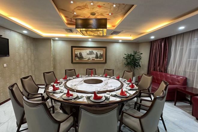 A conference room with a round table, chairs, and a television on the wall.