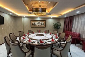 A conference room with a round table, chairs, and a television on the wall. - Jinzun International Hotel (ZAOZHUANG)
