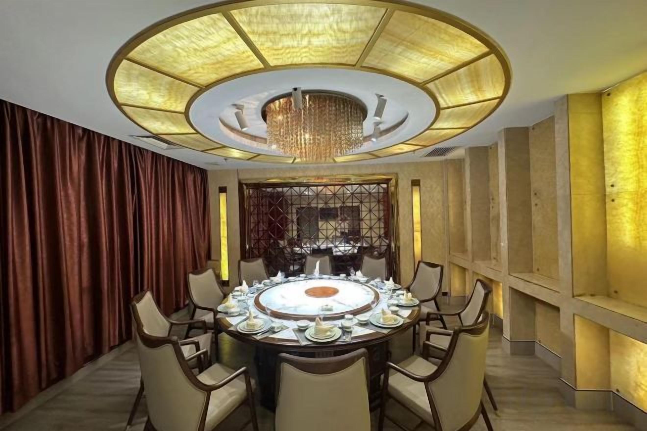 A dining area with a round table, chairs, and a chandelier.