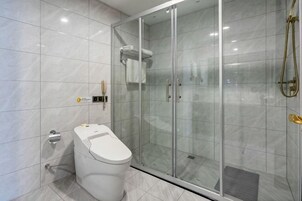 A modern bathroom with a glass-enclosed shower, a toilet, and a wall-mounted towel rack.