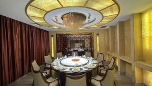 A round dining table with chairs, a chandelier, and a decorative wall panel.
