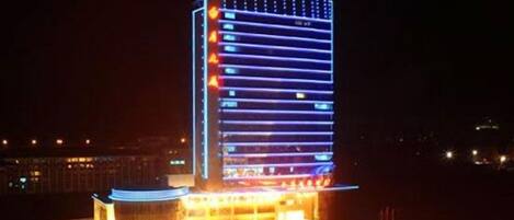 A high-rise building with a modern design, featuring a prominent vertical light strip and a star on top.
