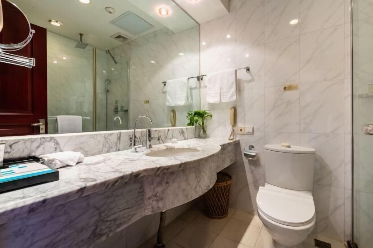 A bathroom with a marble sink, a glass shower enclosure, and a white toilet.