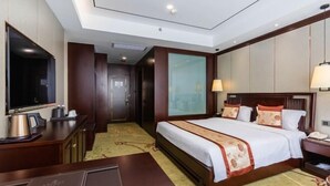 A hotel room with a bed, bedside table, lamp, and a television.