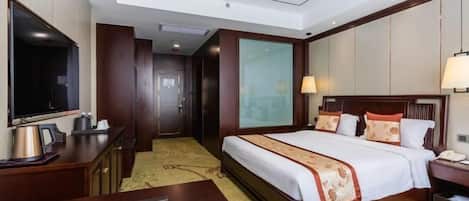 Una habitación de hotel con cama, mesita de noche, lámpara y televisor.