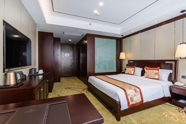 A hotel room with a bed, bedside table, lamp, and a television. - Jinzun International Hotel (ZAOZHUANG)