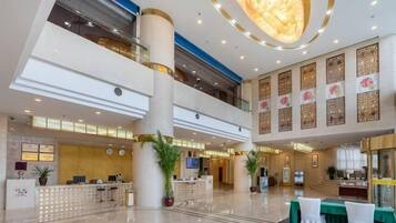 Un'ampia hall con reception, zona salotto e un grande lampadario.